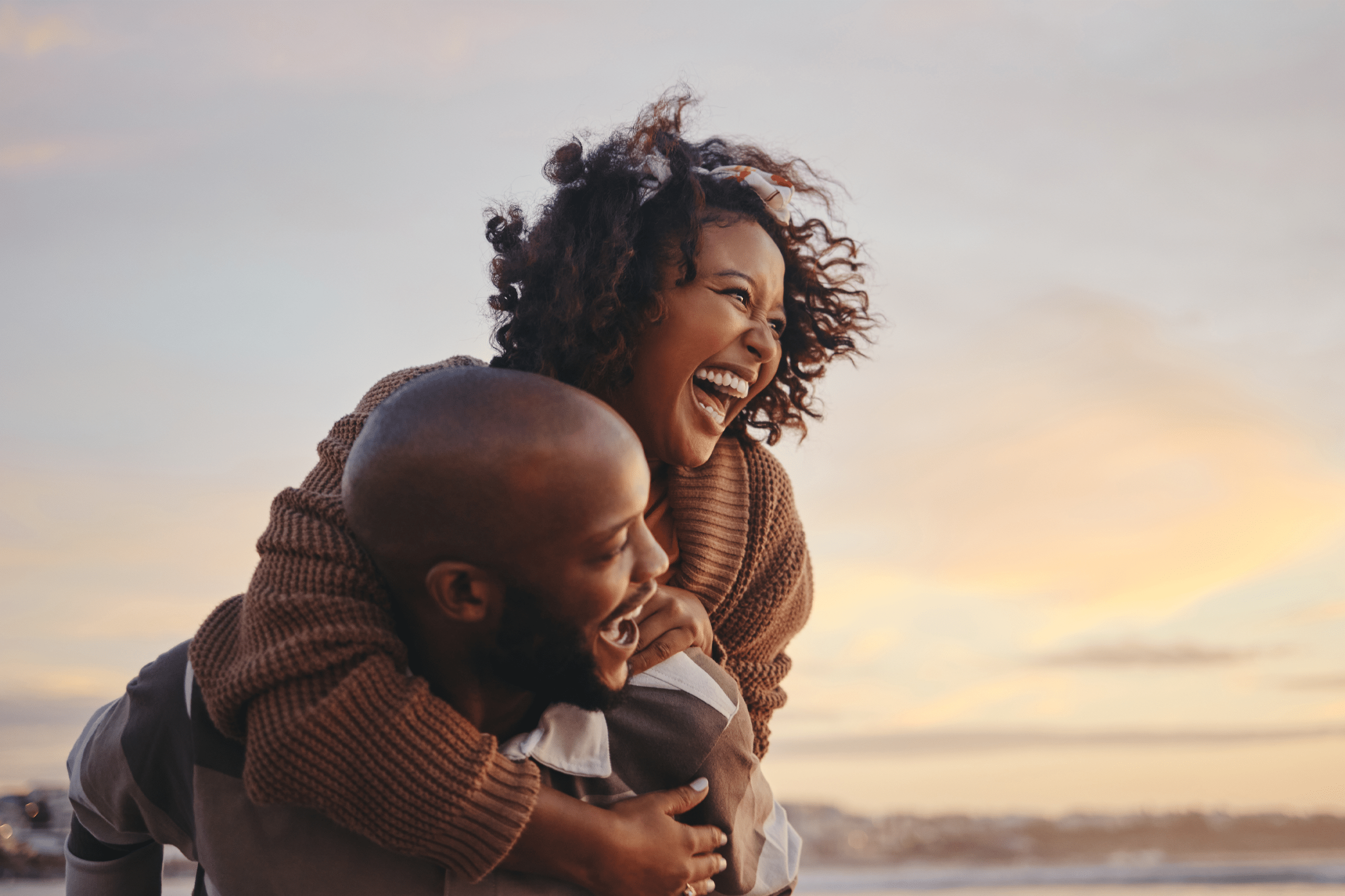Young Couple Piggy Back on Beach at Sunset